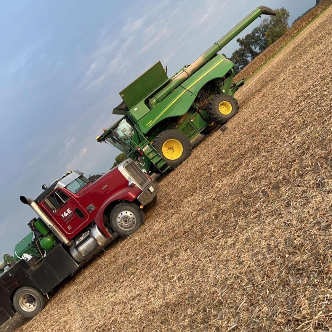 Tractor and truck in a field under a clear blue sky